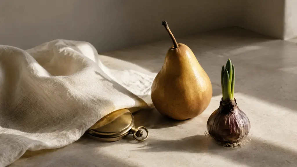 A closed pocket watch rests beneath linen beside a ripe pear and a sprouting bulb in daylight.