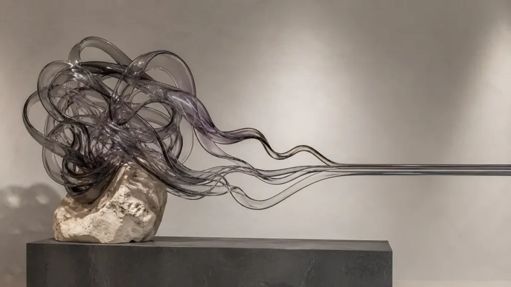 Tangled smoky-glass ribbons gradually settle into calm parallel lines above an ivory stone.