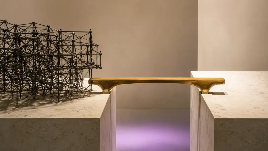 An intricate metal lattice stops at a gap while a simple brass structure connects two platforms.
